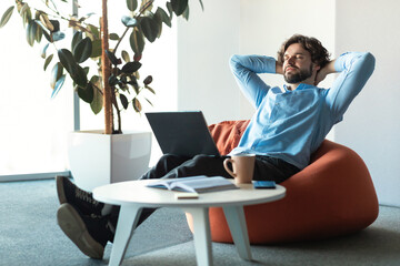 Portrait of smiling business man relaxing on pouf at office