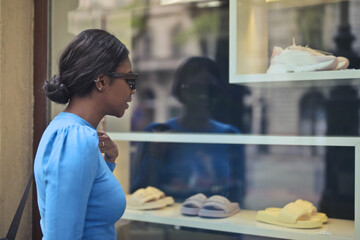 young woman in front of a shop window - obrazy, fototapety, plakaty
