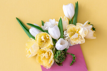 Flowers in an envelope on a colored background, flat lay.