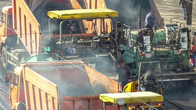 Workers operating asphalt paver machines during road construction and repairing works timelapse