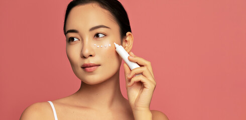 Hydration and skin care concept. Young beautiful asian model posing with applayed cream on her face