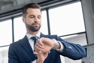 low angle view of bearded businessman checking time on wristwatch.