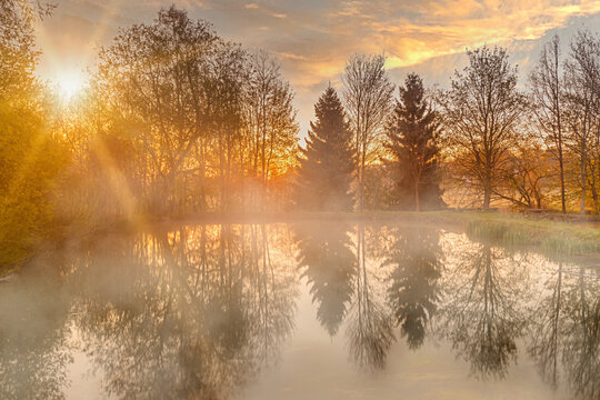 Sunrise over a pond in Bavaria with rising mist