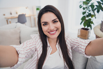 Self-portrait of attractive cheerful long-haired woman sitting on divan resting spending day life at home indoors