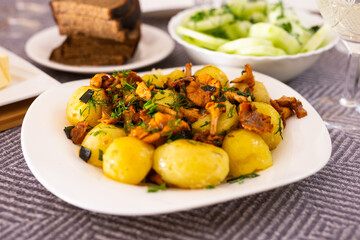 baked potatoes with chanterelles, served with herbs on white plate