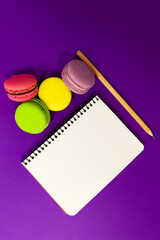 Pencil, macaroons and a notebook on a blue background, place for text.