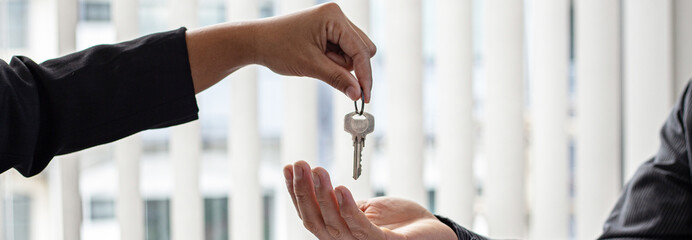Sales manager or real estate agent holds the key handing it to the customer after signing the house...