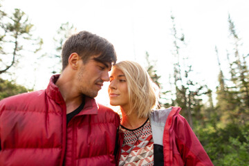 Fototapeta premium Beautiful young woman and man walk, hug and kiss in mountain nature at sunse