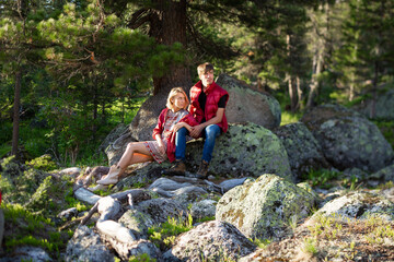 Naklejka premium Beautiful young woman and man walk, hug and kiss in mountain nature at sunse