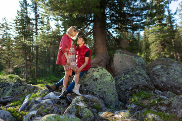 Beautiful young woman and man walk, hug and kiss in mountain nature at sunse