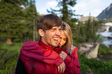 Beautiful young woman and man walk, hug and kiss in mountain nature at sunse