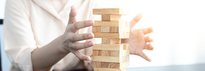 Businessmen carefully placed wooden blocks in a high tower, Protecting a tall wooden tower also...