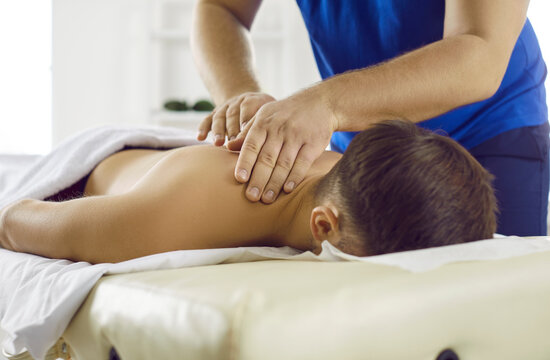 Man getting treatment in health spa. Masseur in modern health center performs therapeutic body massage for young man. Concept of rest, pleasure, health and alternative medicine. Cropped image.