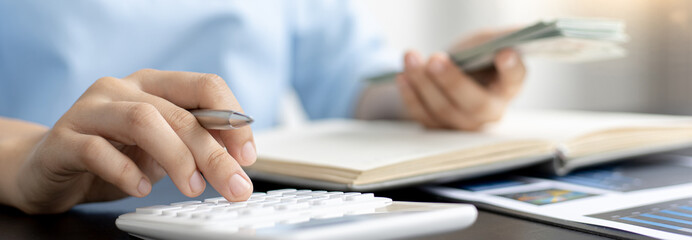 Female housekeepers are calculating using graphs and calculators to make family expenses in order...