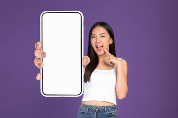 Beautiful Asian brunette woman cute girl in white tank top ,Excited surprised girl showing big smart phone with blank screen , white screen isolated purple background , Mock Up Image
