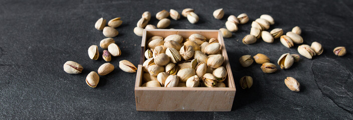 Fototapeta na wymiar Pistachios in a small plate with scattered nuts of almonds around a plate on a vintage wooden table as a background. Pistachio is a healthy vegetarian protein nutritious food. Natural nuts snacks.