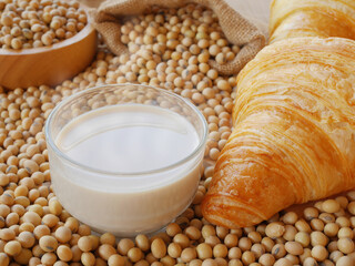 Delicious soy milk on lots of soy beans with sack of soy beans and some croissant and wooden bowl of soy beans