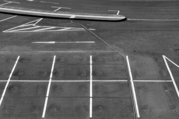 White Lines and arrows painted on grey asphalt ground of an empty Car Park parking lot at Cologne Airport Germany. Black and white greyscale structures typical for modern infrastructure.