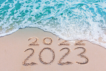 Message Year 2022 replaced by 2023 written on beach sand background. Good bye 2022 hello to 2023 happy New Year coming concept.
 - obrazy, fototapety, plakaty