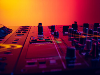 Close-up image of professional dj sound mixer isolated over gradient red yellow background in neon...