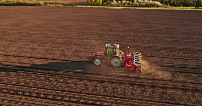 Farmer in tractor seeding corn on agricultural field