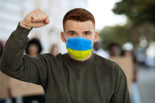 Guy in face mask Ukrainian flag over group of demonstrators