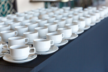 White ceramic mug for drinks in front of the seminar room.Many rows of coffee or tea cups for background.