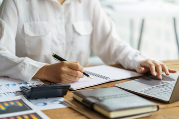 Close-up of business woman hands check company finances and earnings and budget with graph on desk in the office.