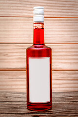 bottle with red drink and blank white label on wooden background.copy space