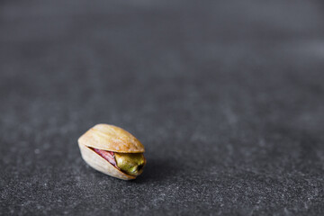 Fototapeta na wymiar One pistachio close-up on dark background. The concept of healthy eating