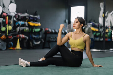Fototapeta na wymiar Beautiful Asian woman in sportswear is doing stretching and warming up before her workout at gym.