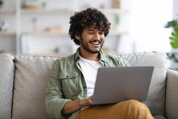 relaxed dark-skinned guy using notebook at home