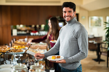 Man picking food at a buffet in a hotel for his breakfast