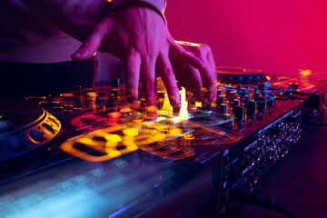 Close-up image of male hands, dj making sounds at night club party with professional sound mixer