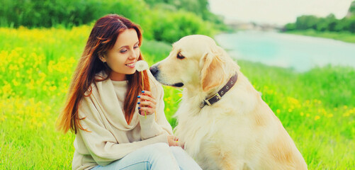 Portrait of happy smiling woman with her Golden Retriever dog on green grass in summer park