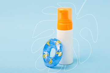 Blank bottle with cream after sun with decorative swimming circle near it.Hand drawing tropical leaf on background.