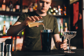 Vintage portrait of bartender creating cocktails at bar. Close up of alcoholic beverage preparation