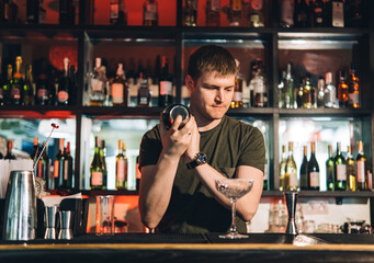 Vintage portrait of bartender creating cocktails at bar. Close up of alcoholic beverage preparation
