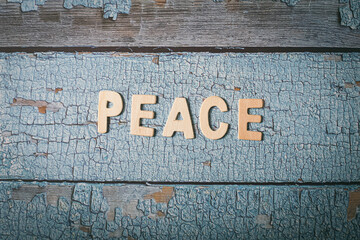 Peace text written with wooden words on a blue texture wooden board