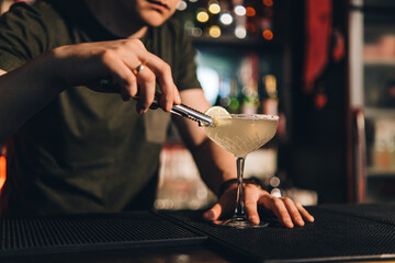 Fototapeta na wymiar Vintage portrait of bartender creating cocktails at bar. Close up of alcoholic beverage preparation
