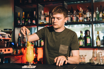 Vintage portrait of bartender creating cocktails at bar. Close up of alcoholic beverage preparation