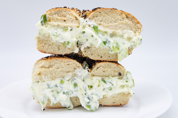 Cut in Half and Stacked New York City Style Toasted Everything Bagel filled with Scallion Cream Cheese on a White Plate