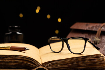 diary of ancient papyrus leaves with spectacles, pen and embossed cover and black background