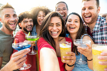 Multi-ethnic group of young people drinking cocktails outside at sunset - Happy friends taking...