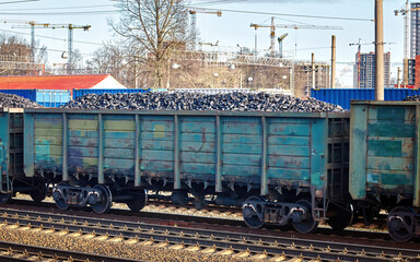 Coal freight train loaded with coal. Train transports fossil fuel. Train cars full of coal at railway station. Coal embargo, ban and restrictions concept.