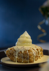 Celebration cake pieces on black dessert plates with white meringue cream on top. Birthday cake and bouquet on the table