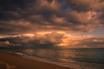 Fototapeta na wymiar Espectacular atardecer en la playa con grandes nubarrones