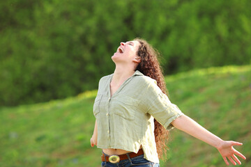Obraz premium Happy woman screaming in a park outstretching arms