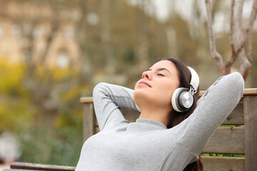 Relaxed teen resting listening to music in a bench