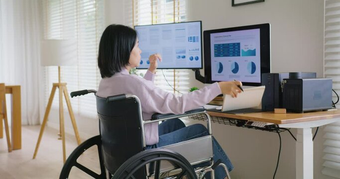 Asian disability woman with wheelchair busy work online multiple screen laptop computer or smart tablet at home in freelance sale data analytic, data science scientist engineer for business